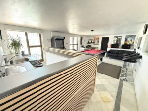Gran salón de juegos con mesa de billar y barra de bar para reuniones en planta baja de chalet