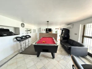Gran salón de juegos con mesa de billar y barra de bar para reuniones en planta baja de chalet