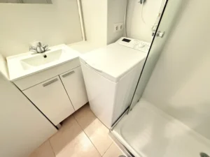 Baño completo con plato de ducha y lavadora en estudio Calypso 1